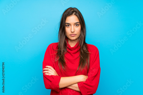 Young woman with red sweater over isolated blue background keeping arms crossed © luismolinero