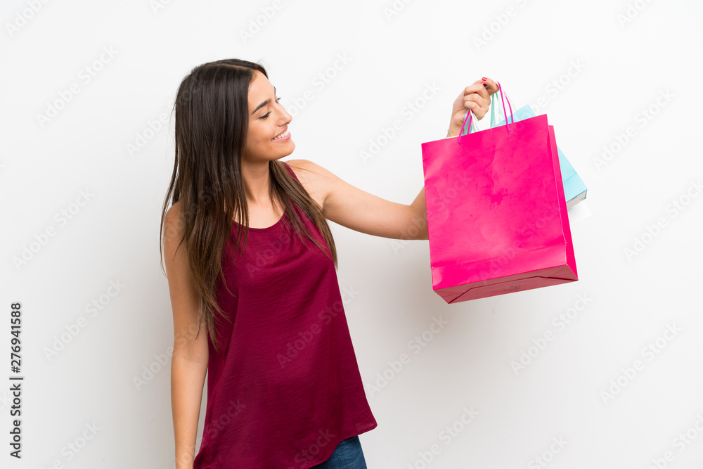 Young woman over isolated white background holding a lot of shopping bags Young woman over isolated white background holding a lot of shopping bags