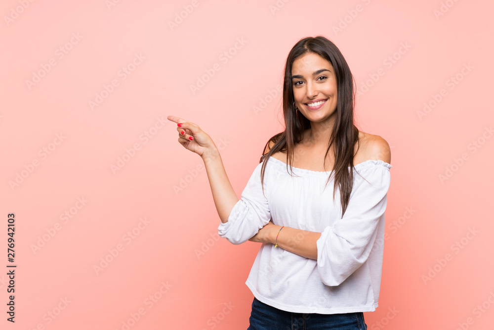 Young woman over isolated pink background pointing finger to the side - obrazy, fototapety, plakaty 