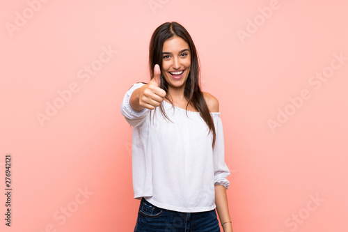 Young woman over isolated pink background with thumbs up because something good has happened photo