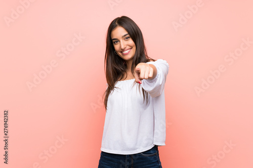 Young woman over isolated pink background points finger at you with a confident expression