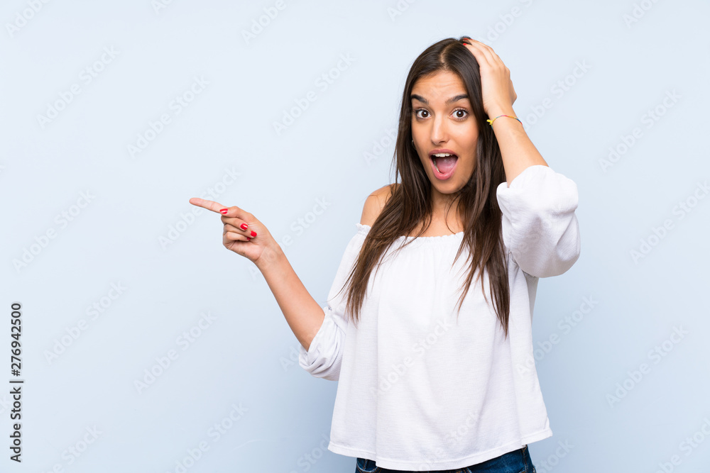 Young woman over isolated blue background surprised and pointing finger to the side Young woman over isolated blue background surprised and pointing finger to the side