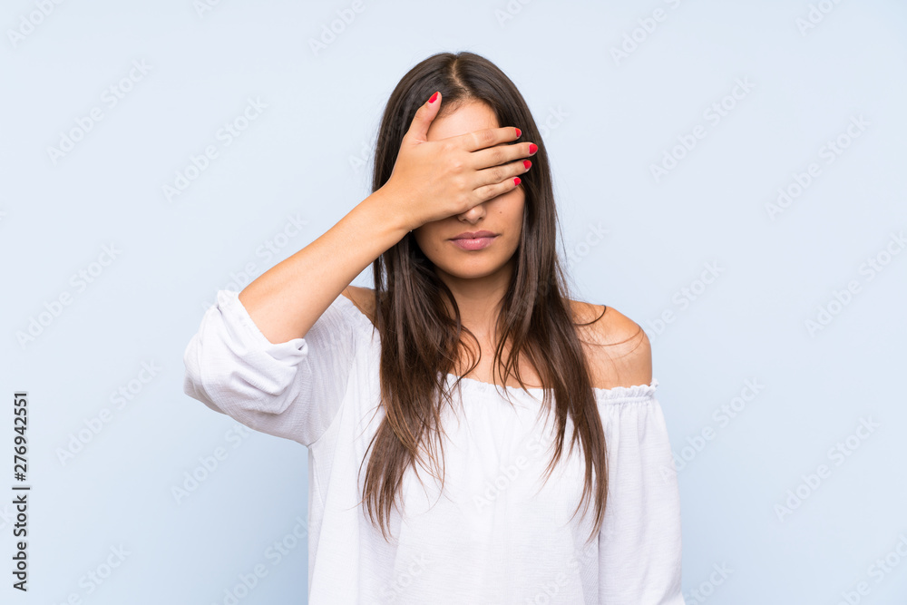 Young woman over isolated blue background covering eyes by hands Young woman over isolated blue background covering eyes by hands