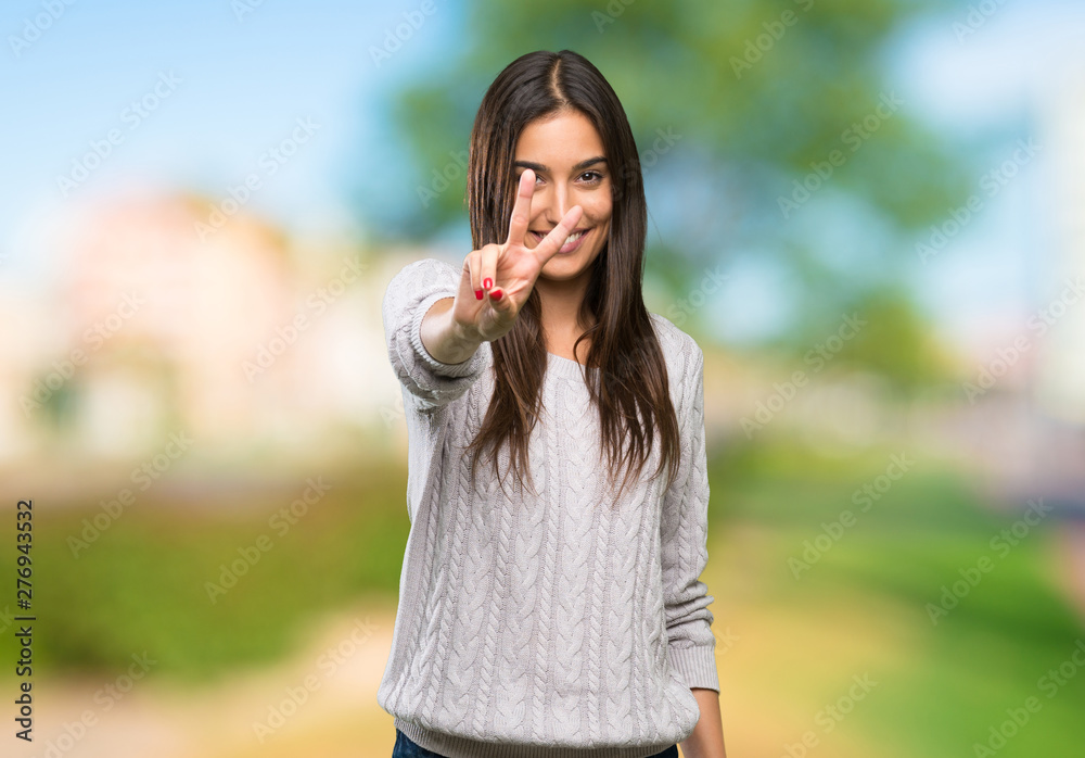 Young hispanic brunette woman smiling and showing victory sign at outdoors Young hispanic brunette woman smiling and showing victory sign at outdoors