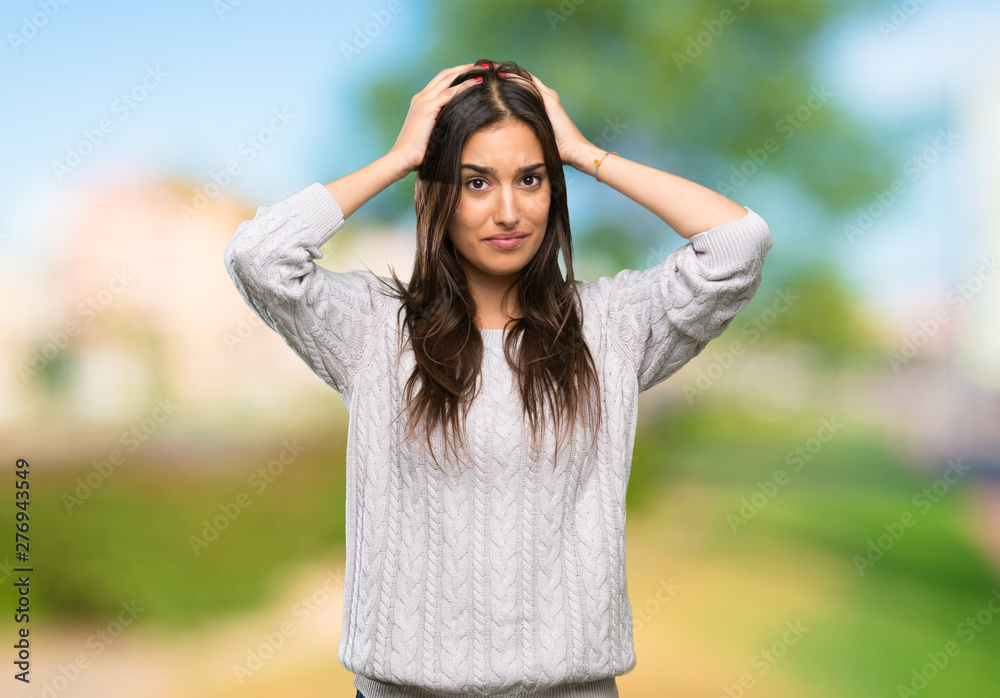 Young hispanic brunette woman frustrated and takes hands on head at outdoors