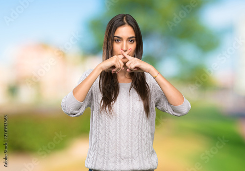 Young hispanic brunette woman showing a sign of silence gesture at outdoors