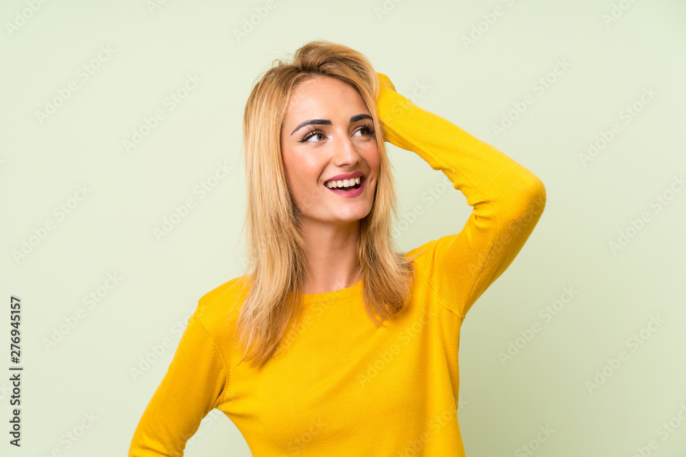 Young blonde woman over isolated green background laughing Young blonde woman over isolated green background laughing