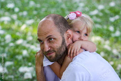 Happy father and daughter spending time together in a park on a summer day and warmly hugging each other. © ANNASTESS