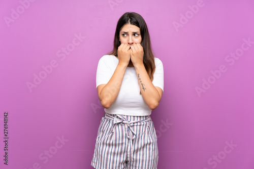 Young woman over isolated purple background nervous and scared putting hands to mouth