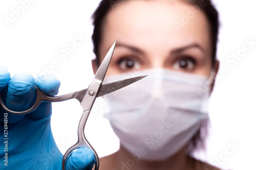 young woman in medical mask on her face, gloves on hands, scissors
