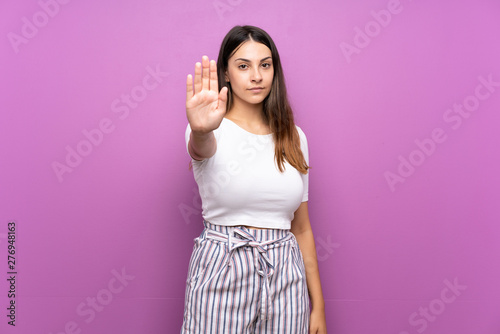 Cuadro en lienzo Young woman over isolated purple background making stop gesture