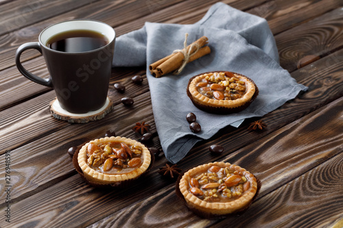 Mini tarts with nuts and honey next to a mug of tea on a wooden background