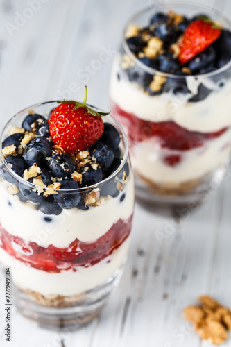 Two pieces of puff glass dessert with granola, mascarpone cream, strawberry, blueberry and walnuts
