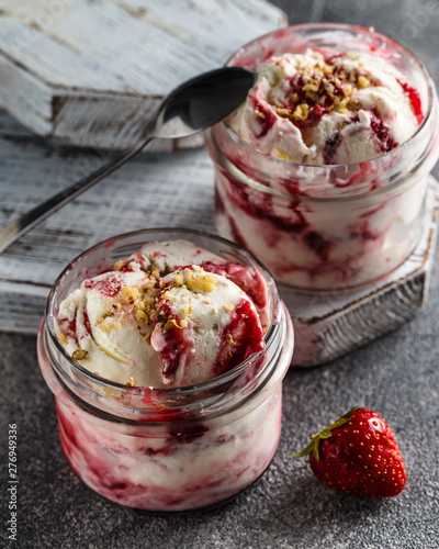 Two jars of strawberry ice cream on grey background