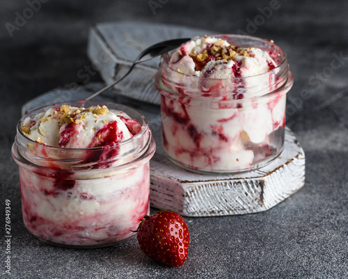Two jars of strawberry ice cream on grey background