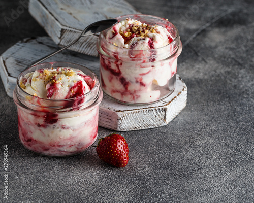 Two jars of strawberry ice cream on grey background