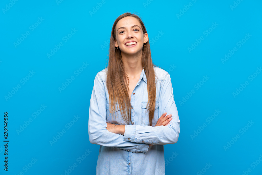Young woman over isolated blue background keeping the arms crossed in frontal position Young woman over isolated blue background keeping the arms crossed in frontal position
