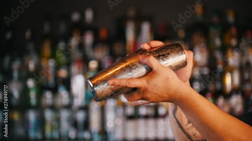 Professional young barman using a pair of glasses prevents cocktail photo
