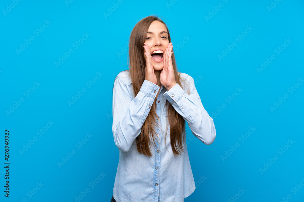Young woman over isolated blue background shouting and announcing something Young woman over isolated blue background shouting and announcing something