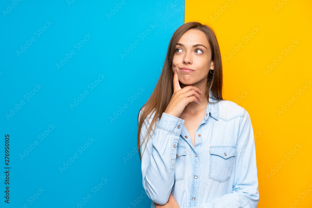 Young woman over colorful background thinking an idea - obrazy, fototapety, plakaty 