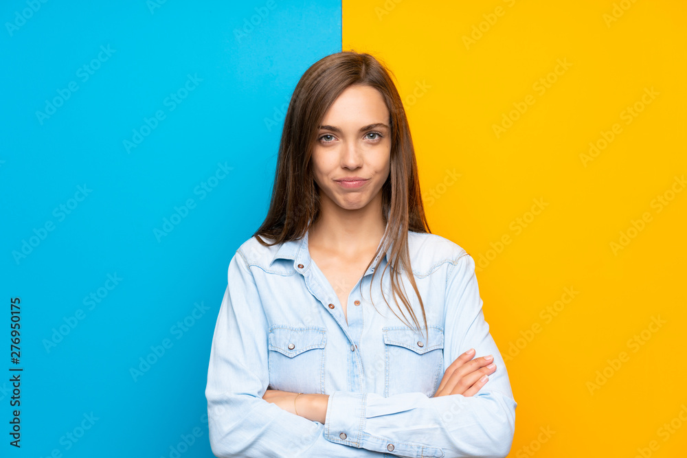 Young woman over colorful background keeping arms crossed Young woman over colorful background keeping arms crossed