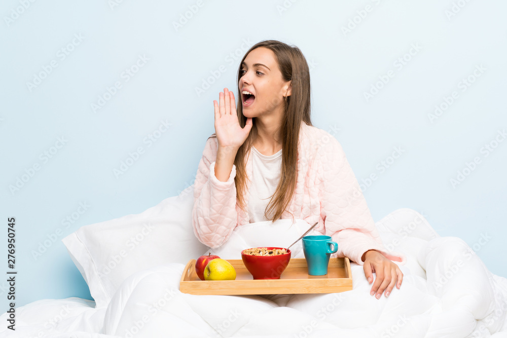 Young woman in dressing gown with breakfast shouting with mouth wide open Young woman in dressing gown with breakfast shouting with mouth wide open