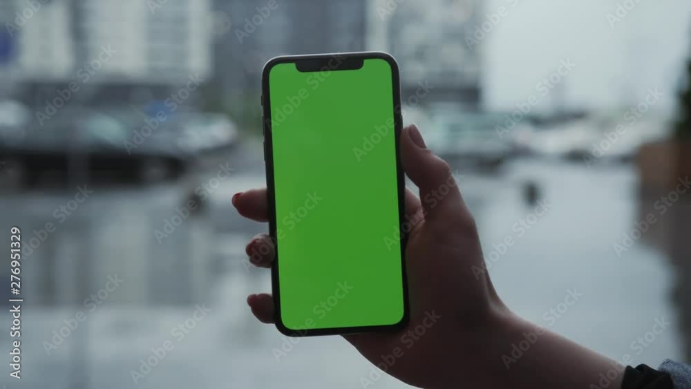 Los Angeles, California - 5 April 2019: Close up view woman hand holding vertically smart phone cellphone with green screen background rain parking cars weather app outside rain trees raindrops Los Angeles, California - 5 April 2019: Close up view woman hand holding vertically smart phone cellphone with green screen background rain parking cars weather app outside rain trees raindrops