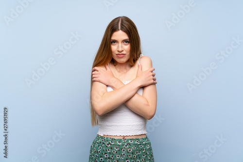 Young woman over isolated blue background freezing