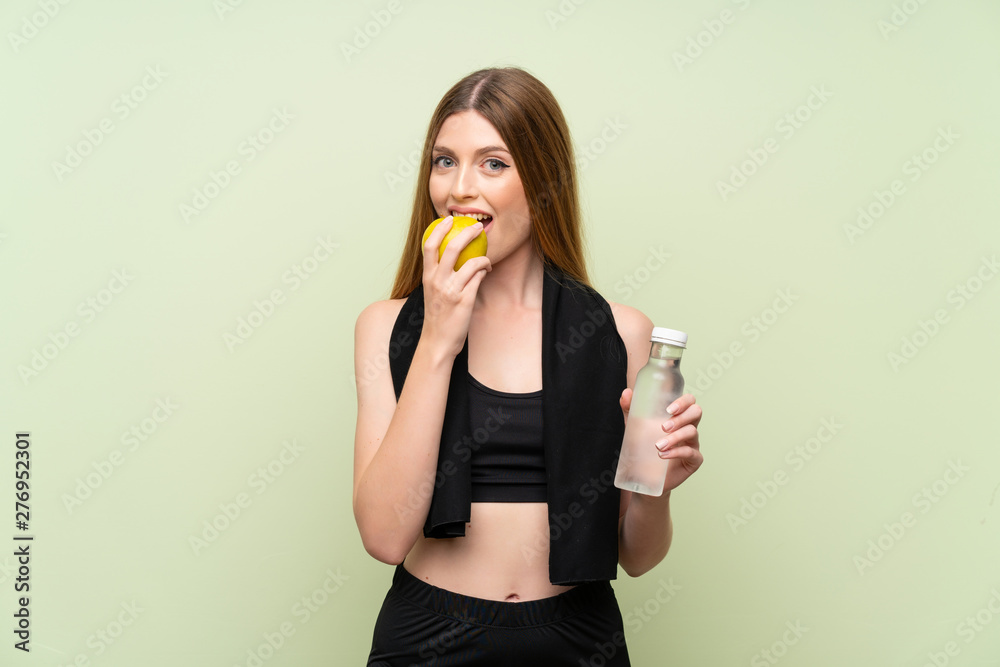 Young sport woman over isolated green background with an apple Young sport woman over isolated green background with an apple