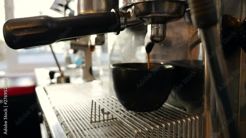 Pouring coffee stream from professional machine in cup.