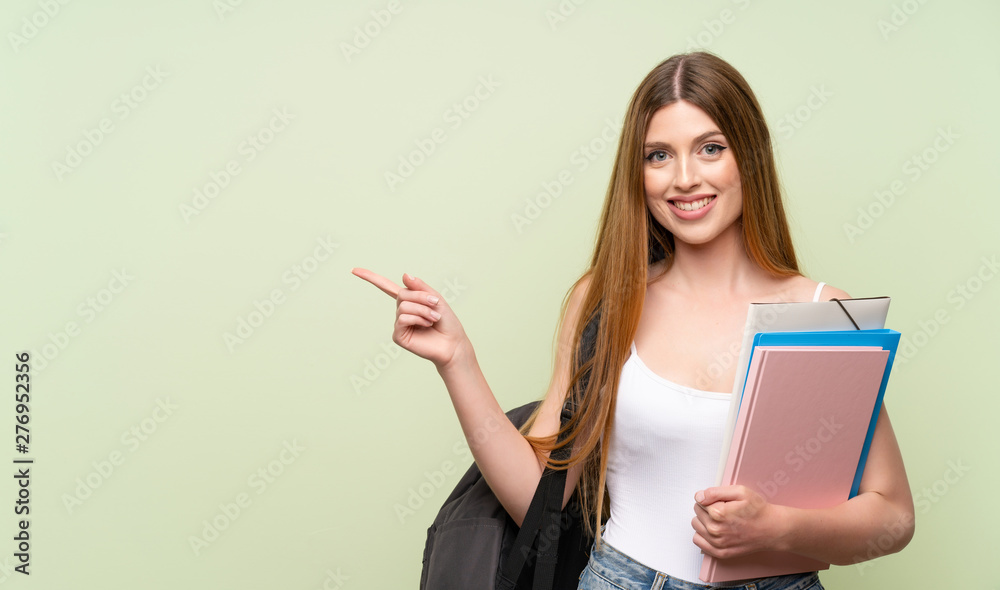Young student woman over isolated green background pointing finger to the side Young student woman over isolated green background pointing finger to the side