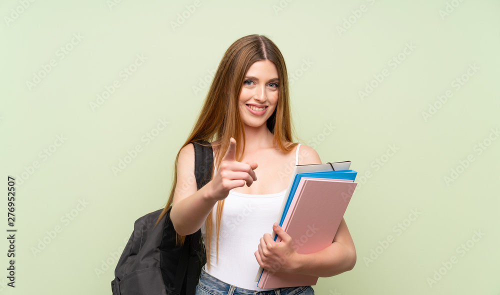 Young student woman over isolated green background points finger at you