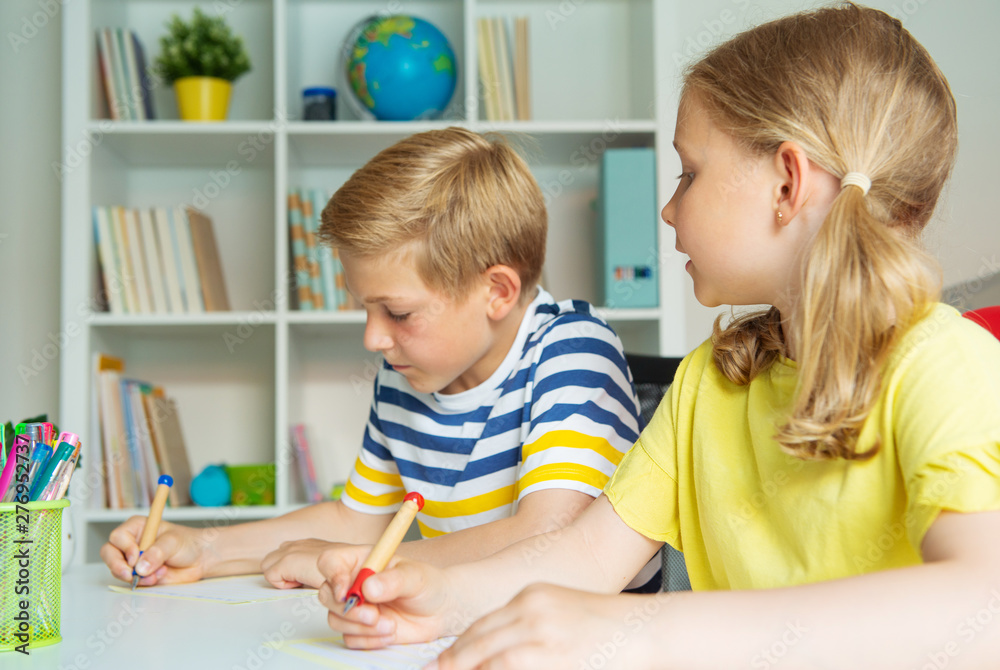Cute schoolchildren are came back to school and learning at the table in classroom Cute schoolchildren are came back to school and learning at the table in classroom