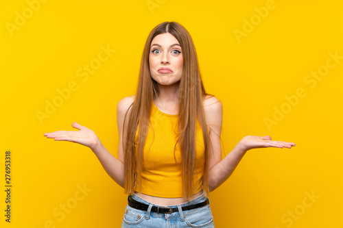 Young woman over isolated yellow background having doubts with confuse face expression photo