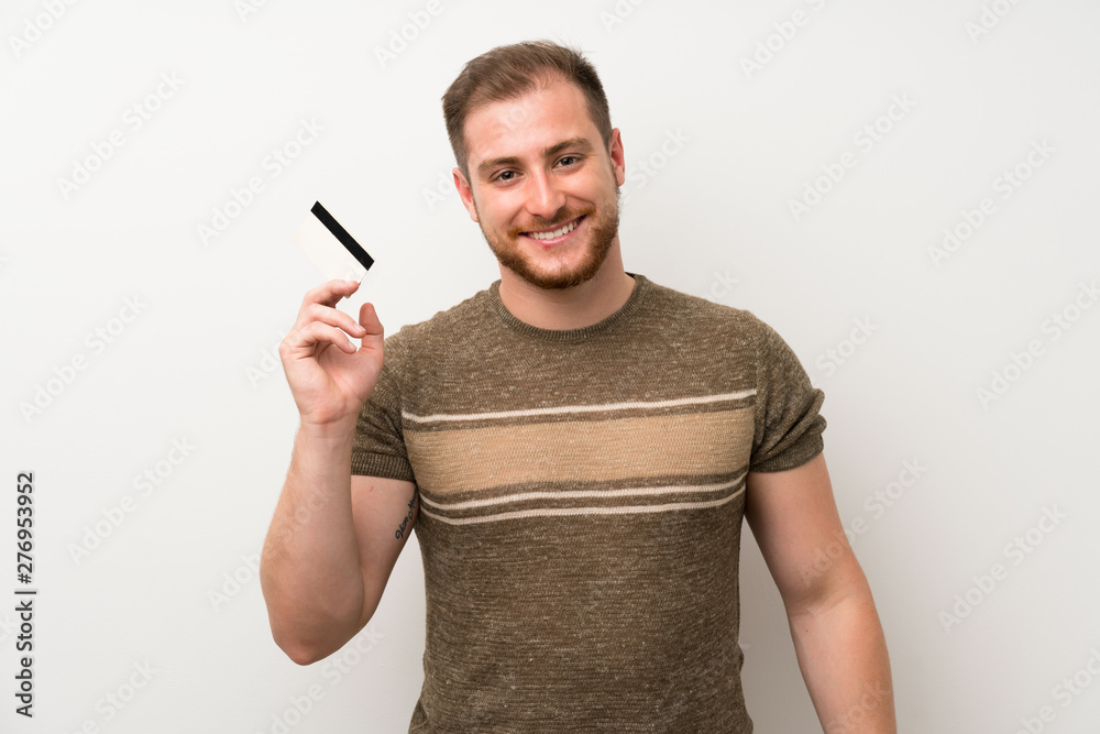 Handsome man over isolated white wall holding a credit card Handsome man over isolated white wall holding a credit card