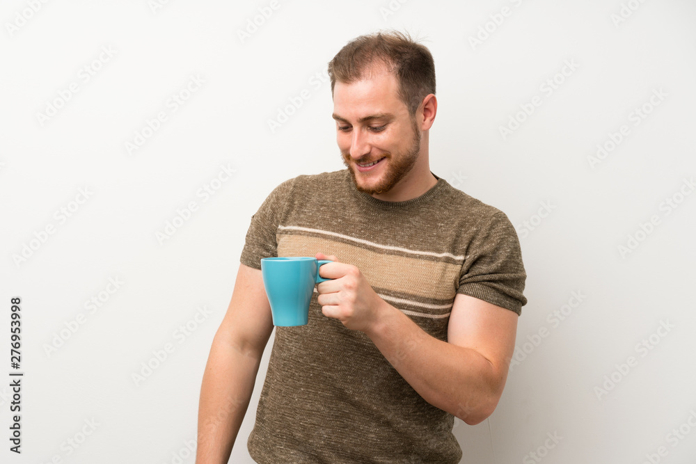 Handsome man over isolated white wall holding hot cup of coffee Handsome man over isolated white wall holding hot cup of coffee