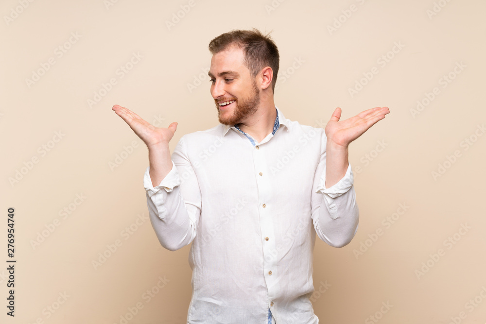Blonde man over isolated background holding copyspace with two hands Blonde man over isolated background holding copyspace with two hands