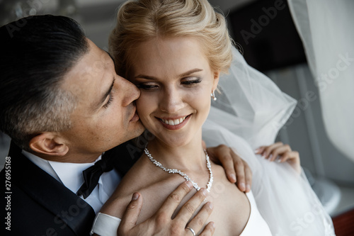 A groom is kissing a laughing bride in the cheek. photo