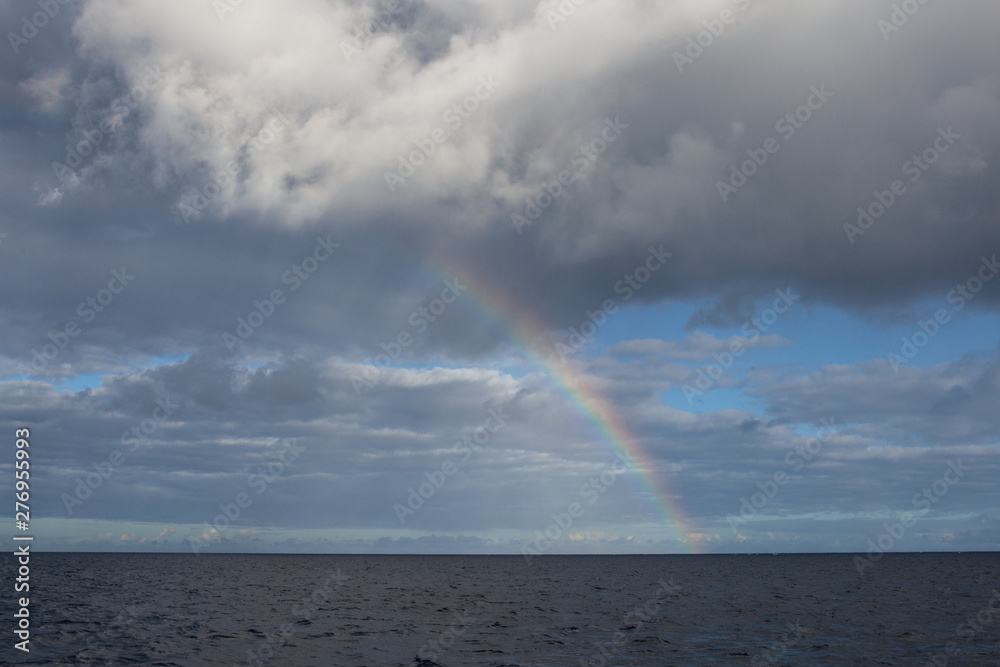A beautiful rainbow appears above the ocean.