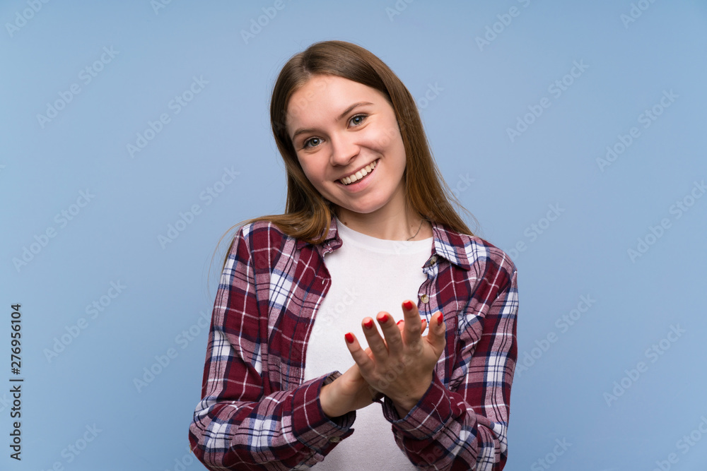 Young woman over blue wall applauding Young woman over blue wall applauding