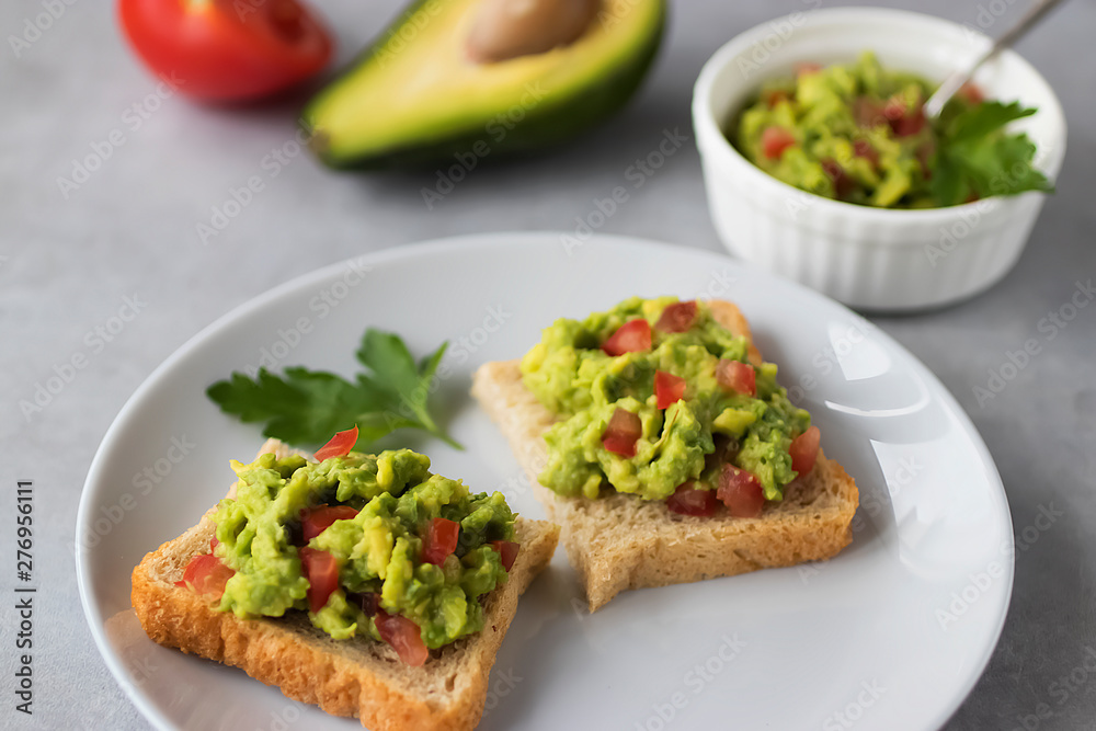 Toasts with an avocado snack and fresh vegetables on a gray background. Toasts with an avocado snack and fresh vegetables on a gray background.