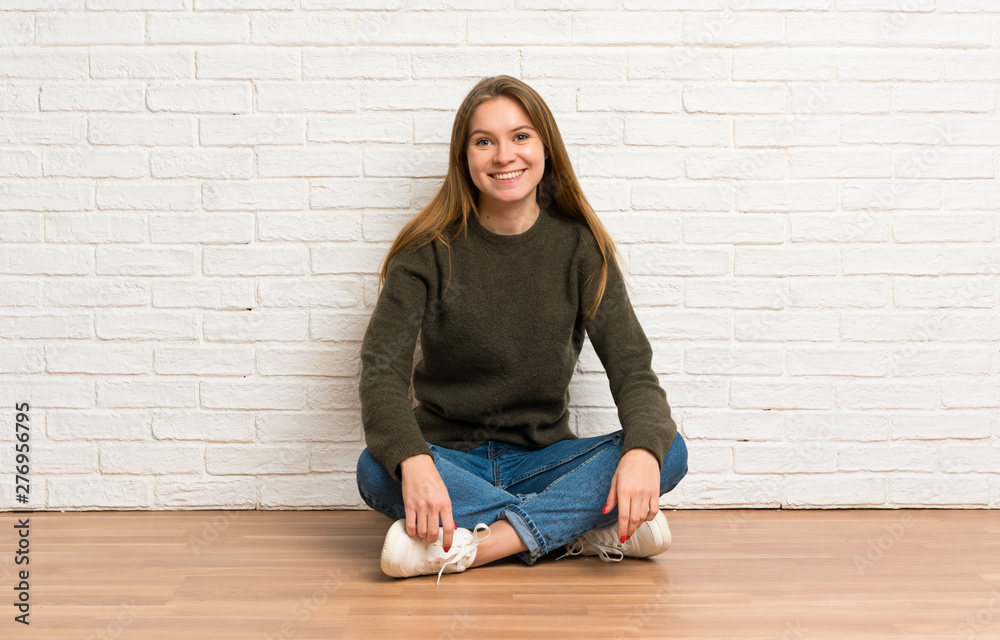 Young woman sitting on the floor keeping the arms crossed in frontal position