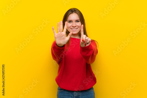 Young woman over yellow wall counting six with fingers