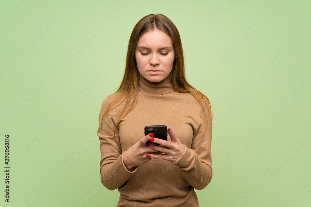 Young woman with turtleneck sweater sending a message with the mobile Young woman with turtleneck sweater sending a message with the mobile