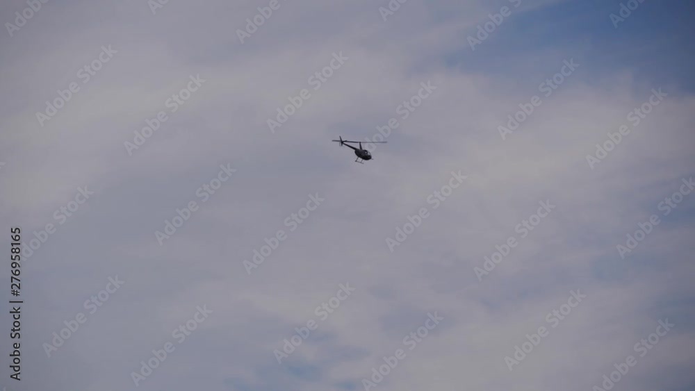 Helicopter ascending over a forest and leaving with a blue cloudy sky and then starting to turn. Helicopter ascending over a forest and leaving with a blue cloudy sky and then starting to turn.