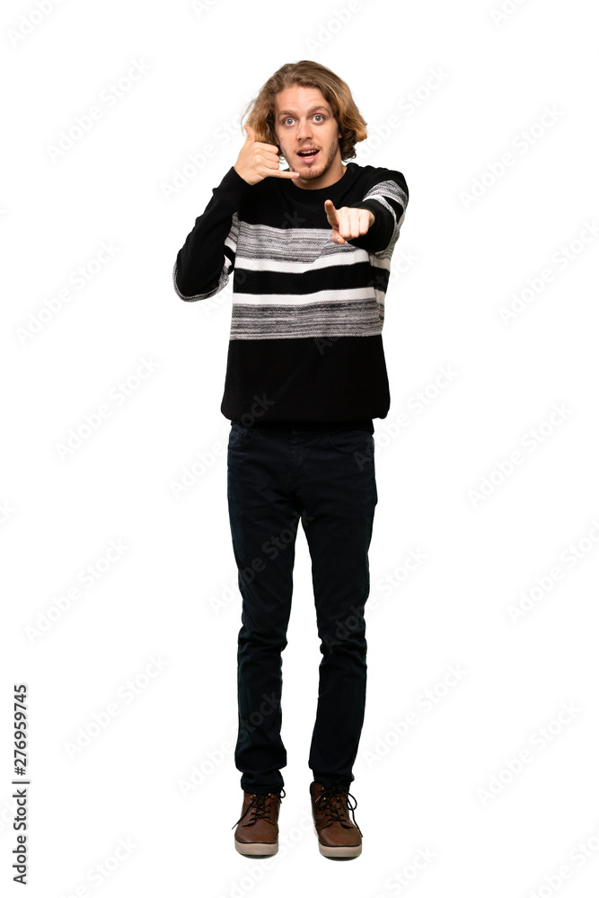 Full-length shot of Blonde man making phone gesture and pointing front over isolated white background Full-length shot of Blonde man making phone gesture and pointing front over isolated white background