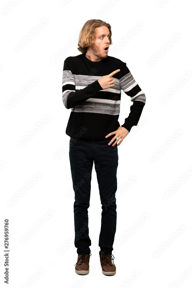 Full-length shot of Blonde man surprised and pointing side over isolated white background Full-length shot of Blonde man surprised and pointing side over isolated white background