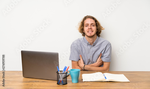 Blonde man with a laptop keeping the arms crossed in frontal position © luismolinero