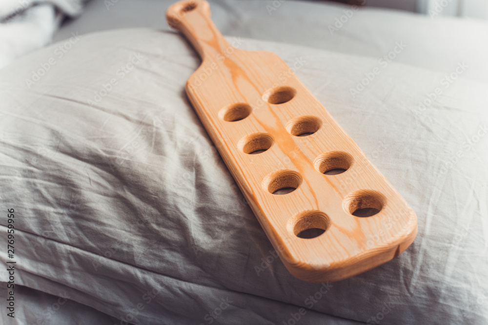 Wooden paddle for spanking on pillow. Domestic discipline image