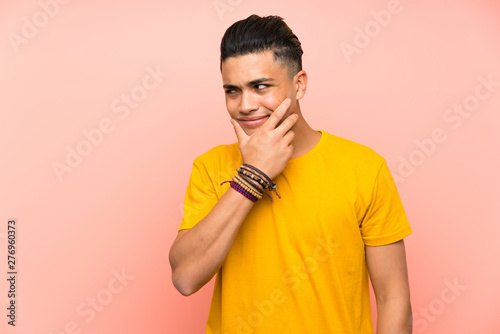 Young man with yellow shirt over isolated pink wall thinking an idea